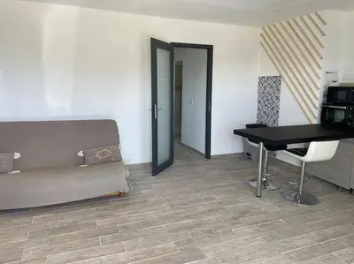 a room with a couch and a table and a desk at U Secondu Appart neuf spacieux au calme in Aléria