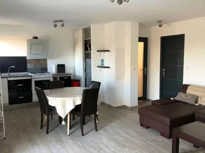 a kitchen and a living room with a table and chairs at U Primu Appartement spacieux au calme Aléria in Aléria