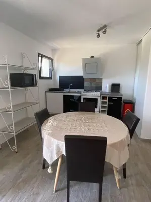 a kitchen with a table and chairs in a room at U Primu Appartement spacieux au calme Aléria in Aléria