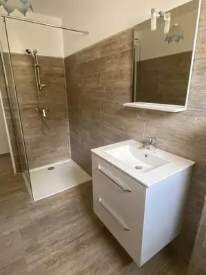 a bathroom with a sink and a shower and a mirror at U Primu Appartement spacieux au calme Aléria in Aléria
