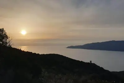 a sun setting over a hill with a body of water at mini villa 72, résidence avec piscine. in Serra-di-Ferro