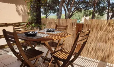 a wooden table and chairs on a patio at mini villa 72, résidence avec piscine. in Serra-di-Ferro
