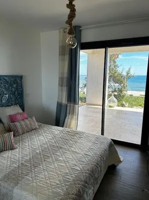 a bedroom with a bed with a view of the ocean at Maison les pieds dans l’eau in Ghisonaccia