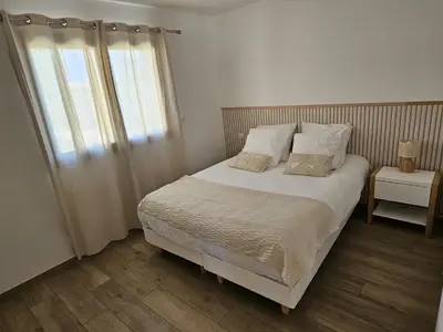 a bedroom with a bed with white sheets and a window at Résidence Villas Chléa in Lucciana