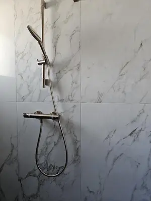 a shower in a bathroom with white marble walls at Résidence Villas Chléa in Lucciana
