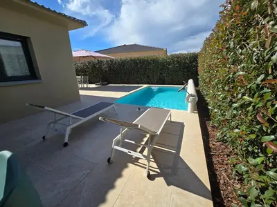 a table and chairs next to a swimming pool at Résidence Villas Chléa in Lucciana