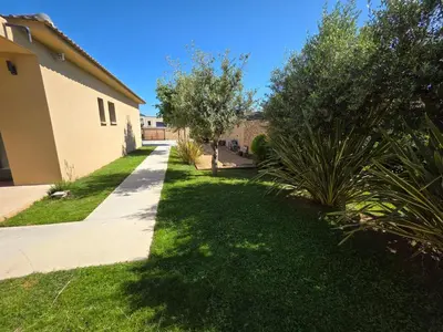 a walkway next to a house with a green yard at Résidence Villas Chléa in Lucciana