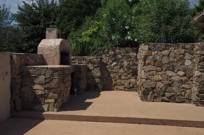 a stone wall with a stone oven in a yard at Villa tout confort avec piscine privée in Ventiseri