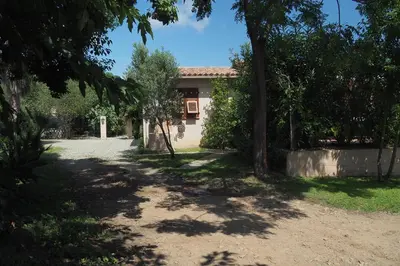 a house in the middle of a yard with trees at Villa tout confort avec piscine privée in Ventiseri