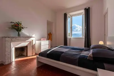 a bedroom with a large bed and a fireplace at Appartement Ajaccien familial in Ajaccio