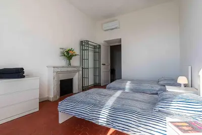 a white bedroom with a bed and a fireplace at Appartement Ajaccien familial in Ajaccio
