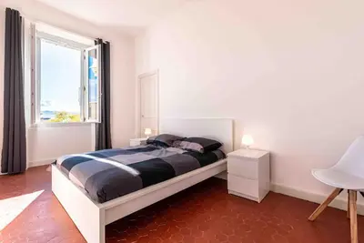 a white bedroom with a bed and a window at Appartement Ajaccien familial in Ajaccio