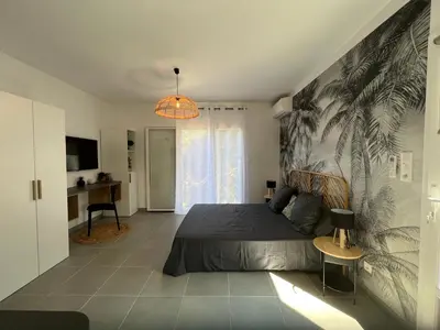 a bedroom with a bed with a palm mural on the wall at Studio 173 - Ajaccio - Campagne in Ajaccio