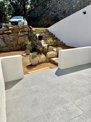 a patio with two white benches and a stone wall at Studio 173 - Ajaccio - Campagne in Ajaccio