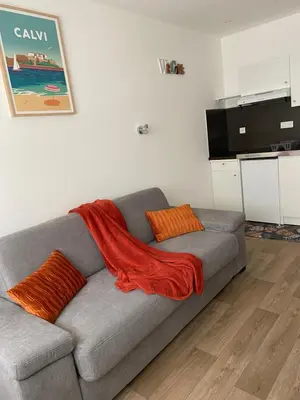 a couch with a red blanket on it in a living room at Résidence City Suites Ajaccio in Ajaccio
