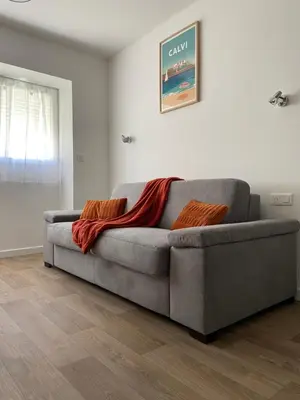 a gray couch with two orange pillows on it in a living room at Résidence City Suites Ajaccio in Ajaccio