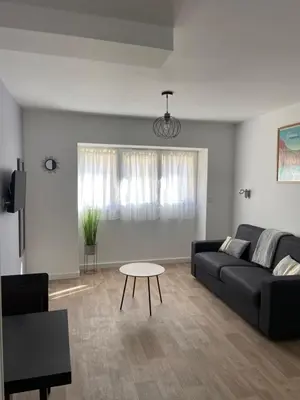 a living room with a black couch and a table at Résidence City Suites Ajaccio in Ajaccio