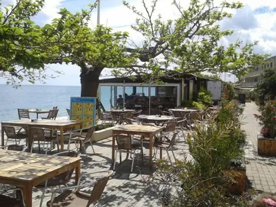 an outdoor patio with tables and chairs next to the water at Location F2 classée 3 étoiles pour des vacances de rêve in San-Nicolao