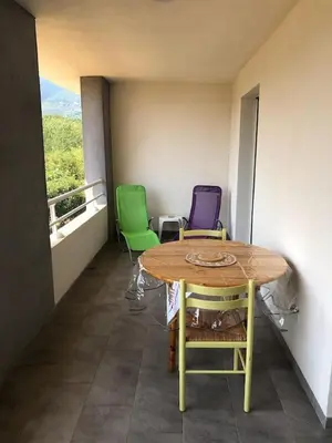 a table and chairs in a room with a balcony at Location F2 classée 3 étoiles pour des vacances de rêve in San-Nicolao