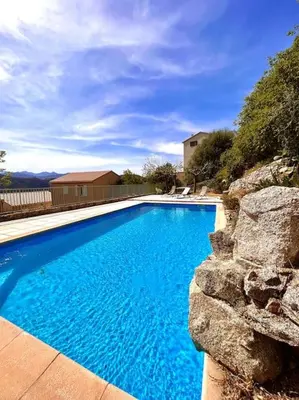 a large blue swimming pool with a stone wall at Appartement 2 chambres à Lama avec Piscine in Lama