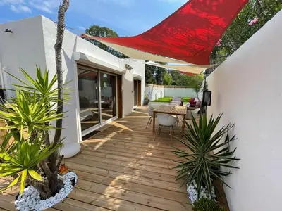 a wooden deck with a table and a red umbrella at Mini Villa Indépendante à 350m de la mer (LAX) in Lucciana