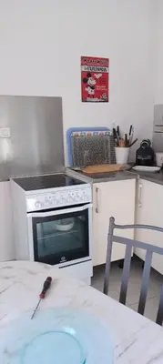 a kitchen with a stove and a table and a table sidx sidx at Appartement Chiola-Plage à pieds-clim in Solaro
