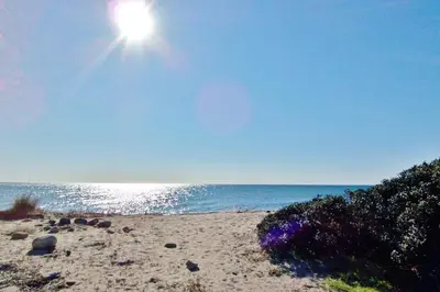 a sandy beach with the sun shining over the ocean at Appartement Chiola-Plage à pieds-clim in Solaro