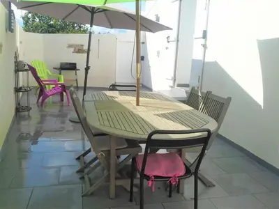 a table and chairs with an umbrella on a patio at Appartement Chiola-Plage à pieds-clim in Solaro