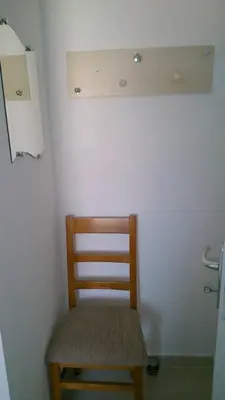a wooden chair sitting in a corner of a room at VILLA T3 bord de mer - vue mer à 500 m de la plage- piscine chauffée A CASETTA DI A SPIAGGIA in Cervione