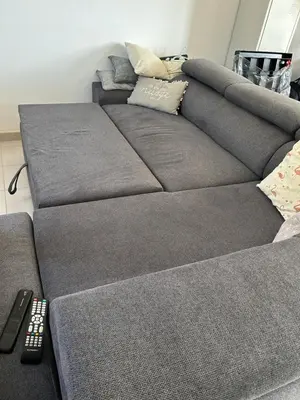 a grey couch with a remote control next to it at VILLA T3 bord de mer - vue mer à 500 m de la plage- piscine chauffée A CASETTA DI A SPIAGGIA in Cervione