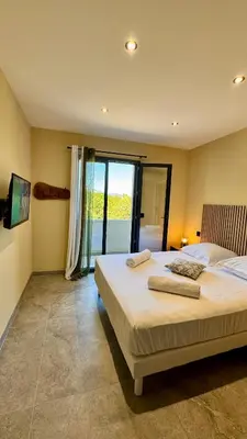 a bedroom with a large bed and a large window at A CASA DI LAURENA piscine chauffée proche St Florent in Vallecalle
