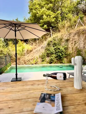 a table with an umbrella and a book on it at A CASA DI LAURENA piscine chauffée proche St Florent in Vallecalle