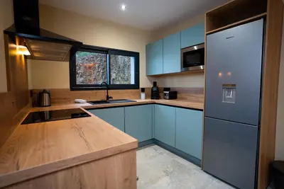 a kitchen with blue cabinets and a sink and a refrigerator at A CASA DI LAURENA piscine chauffée proche St Florent in Vallecalle