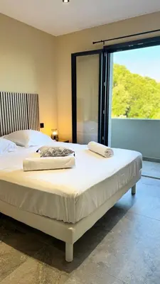 a bedroom with a large white bed with a large window at A CASA DI LAURENA piscine chauffée proche St Florent in Vallecalle