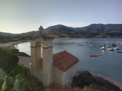 a cross on top of a building with boats in the water at Maison de plage pour 10 personnes de 4 chambres front de mer Corse-du-Sud in Appietto
