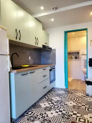 a kitchen with white cabinets and a tile floor at Studio 2A in Ucciani