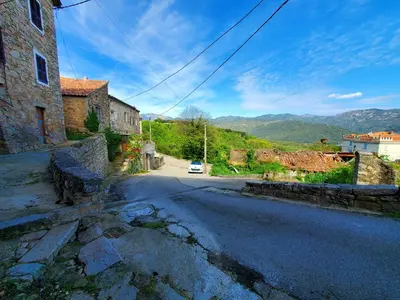 an empty street in a village with a car on the road at Studio 2A in Ucciani