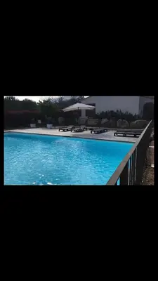 a large blue swimming pool with an umbrella at Appartement proche des plages in Porto-Vecchio