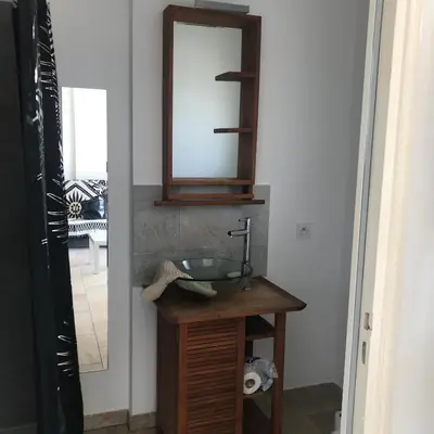 a bathroom with a sink and a mirror on a table at Appartement proche des plages in Porto-Vecchio