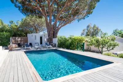 a swimming pool with a tree in the backyard at Villa 4 personnes U Pinu, piscine partagée, 6 kms de porto vecchio in Porto-Vecchio