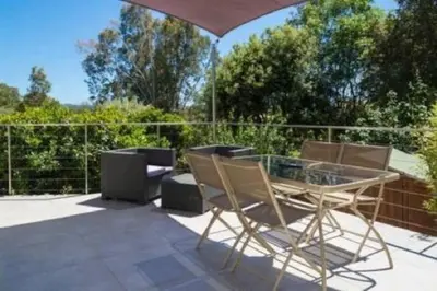 a patio with a glass table and chairs at Villa 4 personnes U Pinu, piscine partagée, 6 kms de porto vecchio in Porto-Vecchio