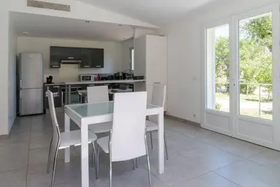a kitchen and dining room with a table and chairs at Villa 4 personnes U Pinu, piscine partagée, 6 kms de porto vecchio in Porto-Vecchio