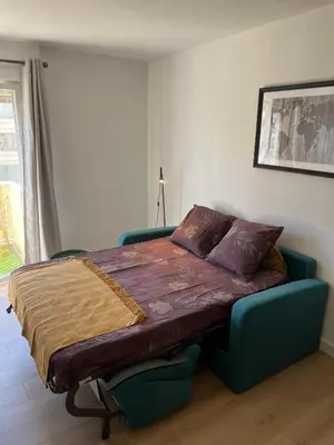 a large bed in a bedroom with a blue couch at Super Studio centre ville d'Ajaccio in Ajaccio