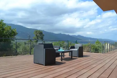 a deck with two chairs and a table with a view at Villa Maremuntagna Porto Vecchio in Porto-Vecchio