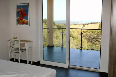 a bedroom with a bed and a view of a balcony at Villa Maremuntagna Porto Vecchio in Porto-Vecchio