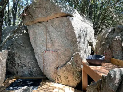 a bowl on a wooden table next to a large rock at CORSICA NATURA #1 in Coti-Chiavari