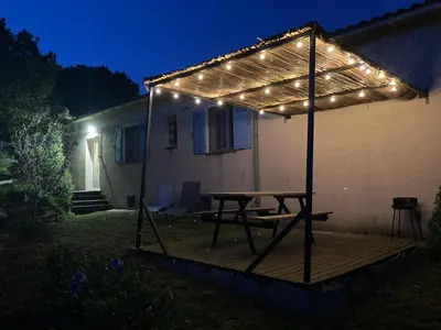 a picnic table with lights on a deck at night at Gîte chez Arthur in Vezzani