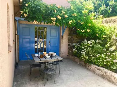 a table and chairs in front of a blue door at Gîte chez Arthur in Vezzani