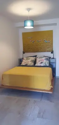 a bedroom with a yellow bed with birds on the wall at Vue de rêve in Calcatoggio
