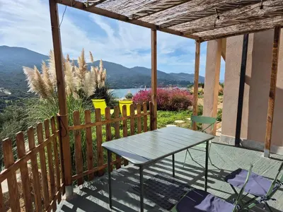a table on a balcony with a view of the mountains at Vue de rêve in Calcatoggio